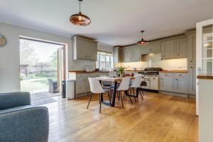 a kitchen with white cabinets and a table and chairs at Walnut Cottage in Brackley