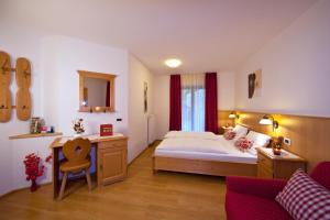 a bedroom with a bed and a desk and a chair at Residence Merk in Selva di Val Gardena