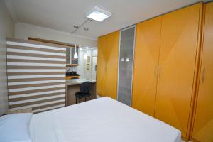 a bedroom with a white bed and wooden cabinets at Garvey Park 1031 - Biensky Imóveis in Brasilia