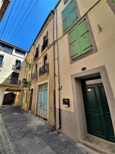 an alley with green doors on a building at Art Lovers Apart Floor 2 in Béziers