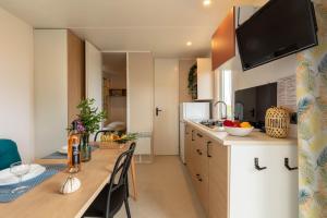 cocina con mesa larga y comedor en Le Cycas, mobil-home neuf avec sa vue dégagée sur les vignes et la mer, en Hyères