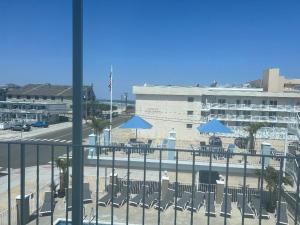 a balcony with chairs and blue umbrellas and a building at Harbor Light Family Resort in North Wildwood