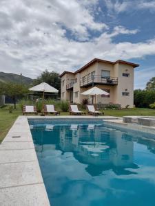 eine Villa mit einem Pool vor einem Haus in der Unterkunft El algarrobo escondido in La Falda
