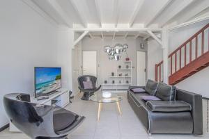 a living room with a couch and chairs and a television at Villa Kaju : grande piscine et proche plage in Sainte-Luce