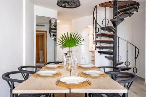 una sala da pranzo con tavolo, sedie e scala a chiocciola di 2 Penthouse Duquesa Marina Manilva Andalucia Spanien a Manilva