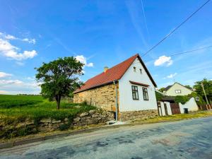 ein weißes Haus mit rotem Dach auf einer Straße in der Unterkunft Potvorovská chalupa in Potvorov