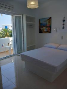 a white bedroom with a bed and a balcony at Klimataria Studios in Agios Prokopios