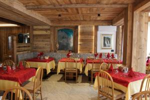 a dining room with tables and chairs with red napkins at Hotel Orso Grigio in Carisolo