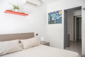 Un dormitorio con una cama blanca y una pintura en la pared en Fabio's BnB, en Milán