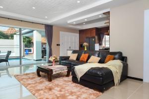 CityHouse-OSCAR,pool villa 4Bedrooms-Jacuzzi-walking Street 10min في جنوب باتايا: غرفة معيشة مع أريكة جلدية وطاولة