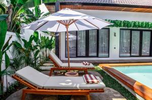 um guarda-sol e espreguiçadeiras ao lado de uma piscina em Hutan Villa by EVDEkimi Ubud em Ubud