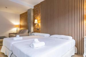 H-A Aparthotel Hotel Quo في مدريد: غرفه فندقيه سريرين عليها مناشف