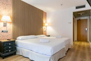 H-A Aparthotel Hotel Quo في مدريد: غرفة نوم بسرير ابيض كبير وارضية خشبية