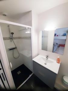 a white bathroom with a shower and a sink at Les Saints Pères in La Rochelle
