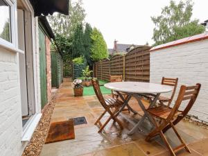 een patio met een tafel en stoelen en een hek bij Gables Cottage in Northwich