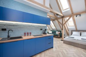 een keuken met blauwe kasten en een bed in een kamer bij Apartament Wincentego Styczyńskiego in Gliwice