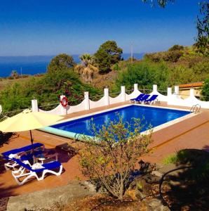 een zwembad met stoelen en een parasol bij Spacious characterful villa with spectacular views in quiet rural setting. in Breña Alta