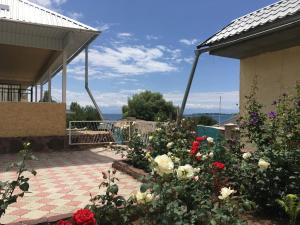 einen Garten mit Rosen und Blumen auf einer Terrasse in der Unterkunft Эдем in Tscholponata
