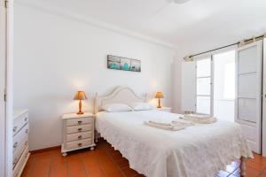 ein weißes Schlafzimmer mit einem weißen Bett und einem Fenster in der Unterkunft Apartamentos Atlantico by Umbral in Vila Nova de Milfontes