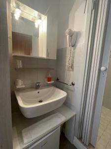 La salle de bains est pourvue d'un lavabo blanc et d'un miroir. dans l'établissement Hotel Carinthia, à Lido di Jesolo