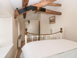 a bedroom with a white bed and wooden beams at The Annexe in Soutergate