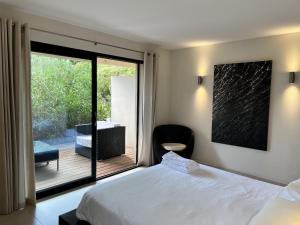 a bedroom with a bed and a balcony with a chair at Nature & Design in Bonifacio