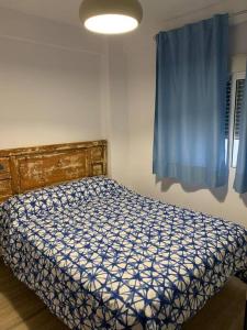 um quarto com uma cama e uma cortina azul em Ideal apartamento en el Barrio de las Delicias em Málaga