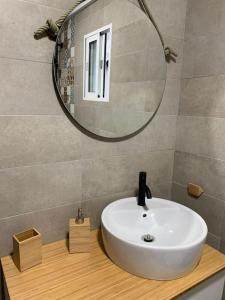 um lavatório de casa de banho com um espelho redondo por cima em Ideal apartamento en el Barrio de las Delicias em Málaga