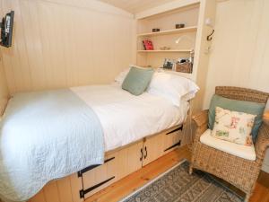 a small bedroom with a bed and a chair at Shepherd's Hut in Castleton