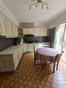 cocina con armarios blancos, mesa y sillas en La maison ensoleillée en Rivesaltes