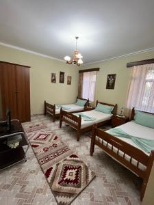 a room with four beds and a television in it at Guest House Adi Doga in Berat