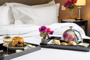 a tray of food and wine on a bed at Hôtel Madeleine Plaza in Paris