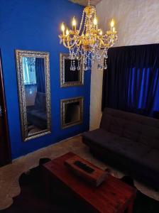 een blauwe woonkamer met een kroonluchter en een tafel bij Pousada Chalé da Montanha São Thomé das Letras in São Thomé das Letras