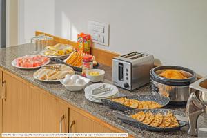 a kitchen counter with a buffet of food on it at Greenotel Rooms Hazira, Surat in Surat