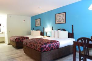 um quarto de hotel com duas camas e uma cadeira em Hilltop Inn & Suites - North Stonington em North Stonington