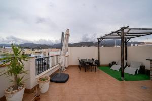 - un balcon avec une table, des chaises et un parasol dans l'établissement Apartamento Cantarero, à Nerja