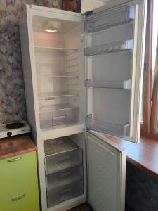 an empty refrigerator with its door open in a kitchen at Glinki 33 Apartments in Semey