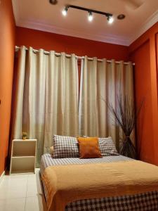 Schlafzimmer mit einem Bett mit orangefarbenen Wänden und Vorhängen in der Unterkunft Bohemian Greenwood Gombak in Batu Caves