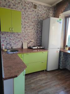 a kitchen with green cabinets and a white refrigerator at Glinki 33 Apartments in Semey