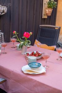a pink table with a bowl of fruit and wine glasses at 1700-talshus i två plan med egen innergård i Visby innerstad in Visby