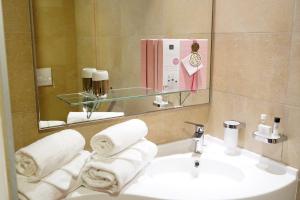 a bathroom with a sink and a mirror and towels at Appart One Uzès in Uzès