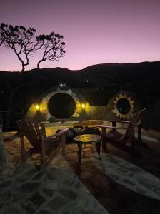 een patio met 2 stoelen en 's avonds een tafel bij Pousada Chalé da Montanha São Thomé das Letras in São Thomé das Letras