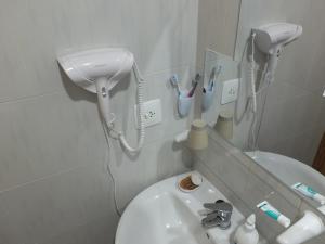 a bathroom with a sink with a blow dryer and tooth brushes at Neptuno Playa San Antonio in Cullera +19 photos