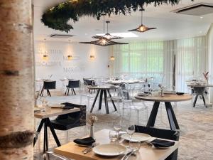 a restaurant with tables and chairs in a room at Lancelot & Spa - Domaine du Roi Arthur in Ploërmel