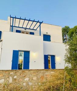 a white house with blue doors and a stone wall at Limni No 2 self catering apartment in Posidhonía