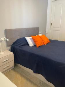 Una cama con dos almohadas naranjas encima. en Encantador Piso con Terraza y Piscina, en Benalmádena