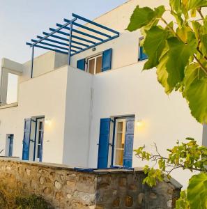 a white house with blue accents on a stone wall at Limni No 2 self catering apartment in Posidhonía