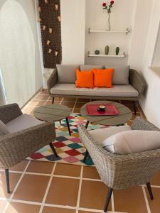sala de estar con sofá, sillas y alfombra en Encantador Piso con Terraza y Piscina, en Benalmádena
