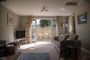 a living room with a couch and a sliding glass door at Cygnets Nest in Worstead