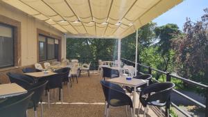 a restaurant with tables and chairs on a balcony at Pension Parrilla Casa Vicente in Tineo
